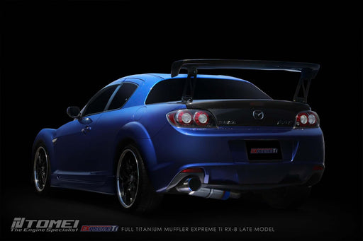 Tomei Expreme Titanium Exhaust System for RX-8 SE3P Late Model 13B-MSP on a blue RX-8 showcasing its performance design.