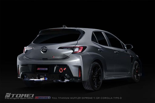 Tomei Expreme Titanium Exhaust System Type-D Dual For Toyota GR Corolla installed on a sleek gray hatchback.